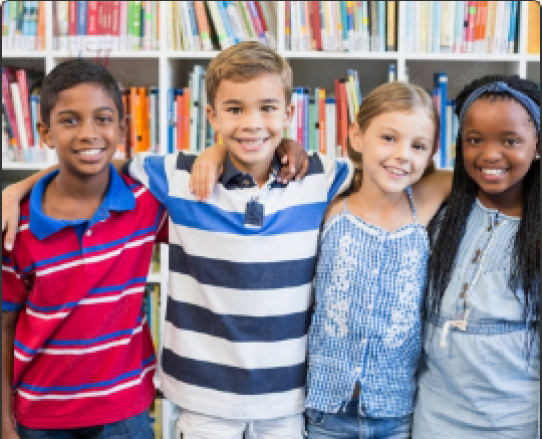A group of four kids smiling for a picture while standing in the library