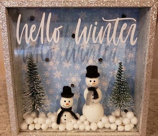 Wooden shadow box with a large and small snowman, two trees and snow balls. 
