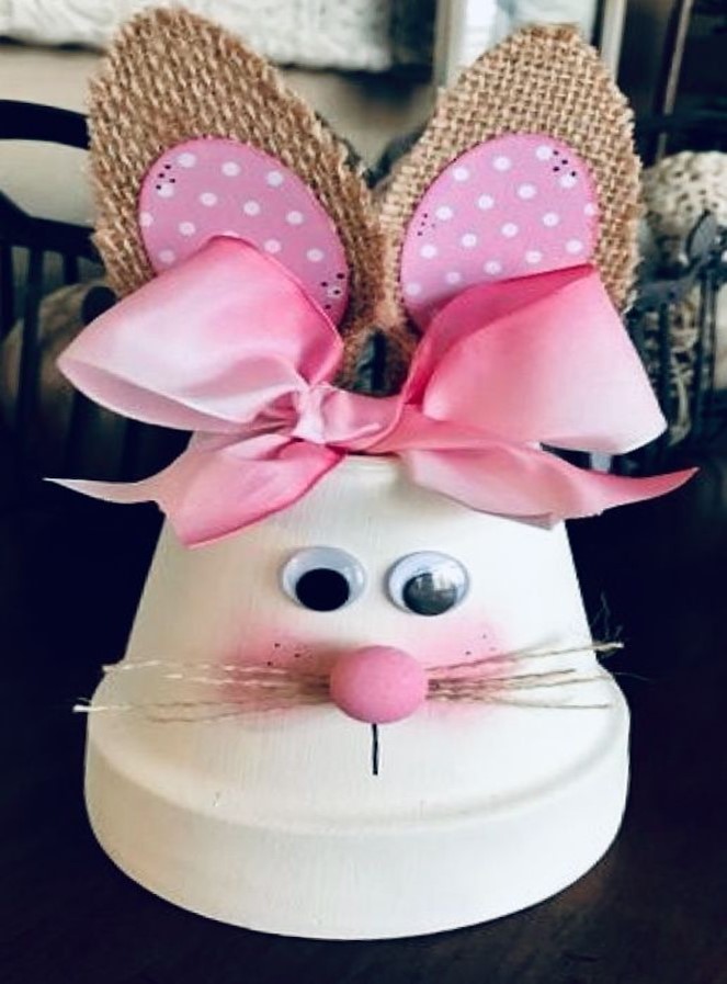 White bunny made from a clay pot with a pink nose and bow. Ears made from burlap and pink material. 