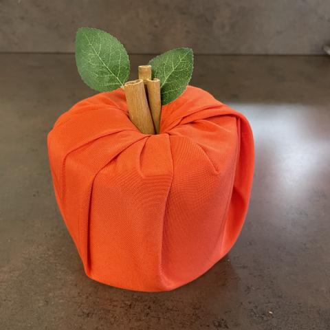 Orange pumpkin craft made from roll of toilet paper and fabric. 