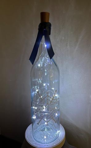Clear wine bottle with fairy lights and a blue ribbon 
