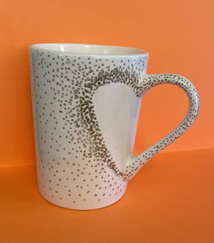 White mug with gold dots and a heart shaped handle. 