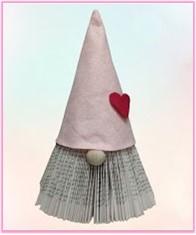 Book folded into a gnome with a pink hat and a red heart on the hat. 